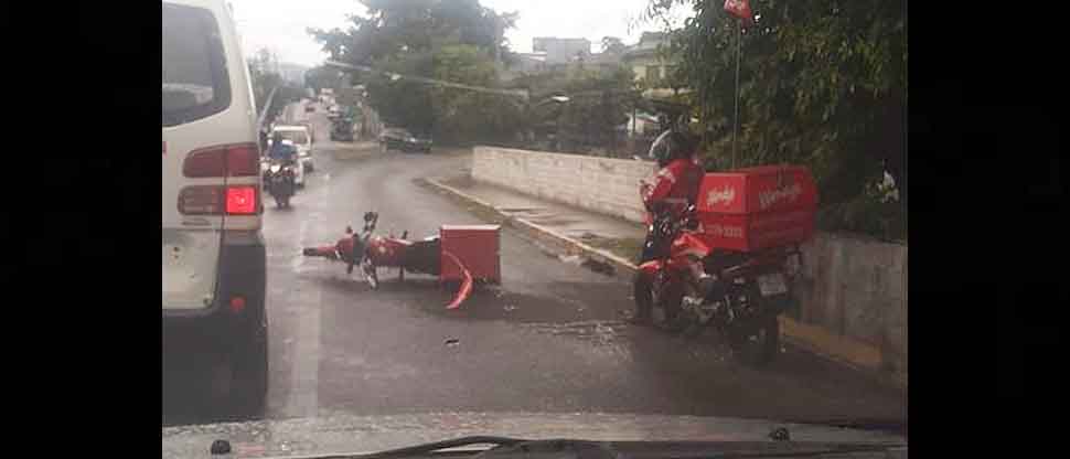Motociclista repartidor de comida queda sobre el pavimento tras ser arrollado por un vehículo
