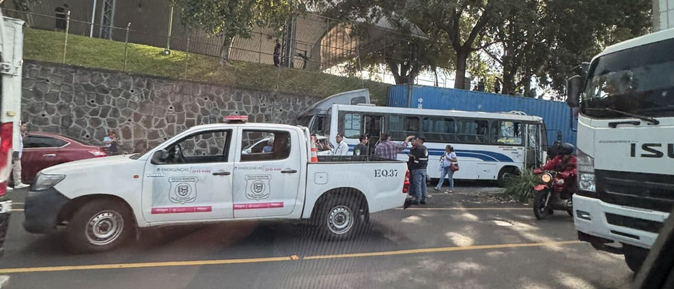 Rastra se pasa llevando varios carros y un microbús en frente de la UCA