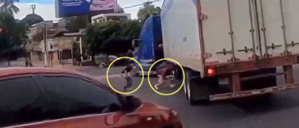 Peatones arriesgan sus vidas al cruzar la calle por debajo de una rastra en San Salvador